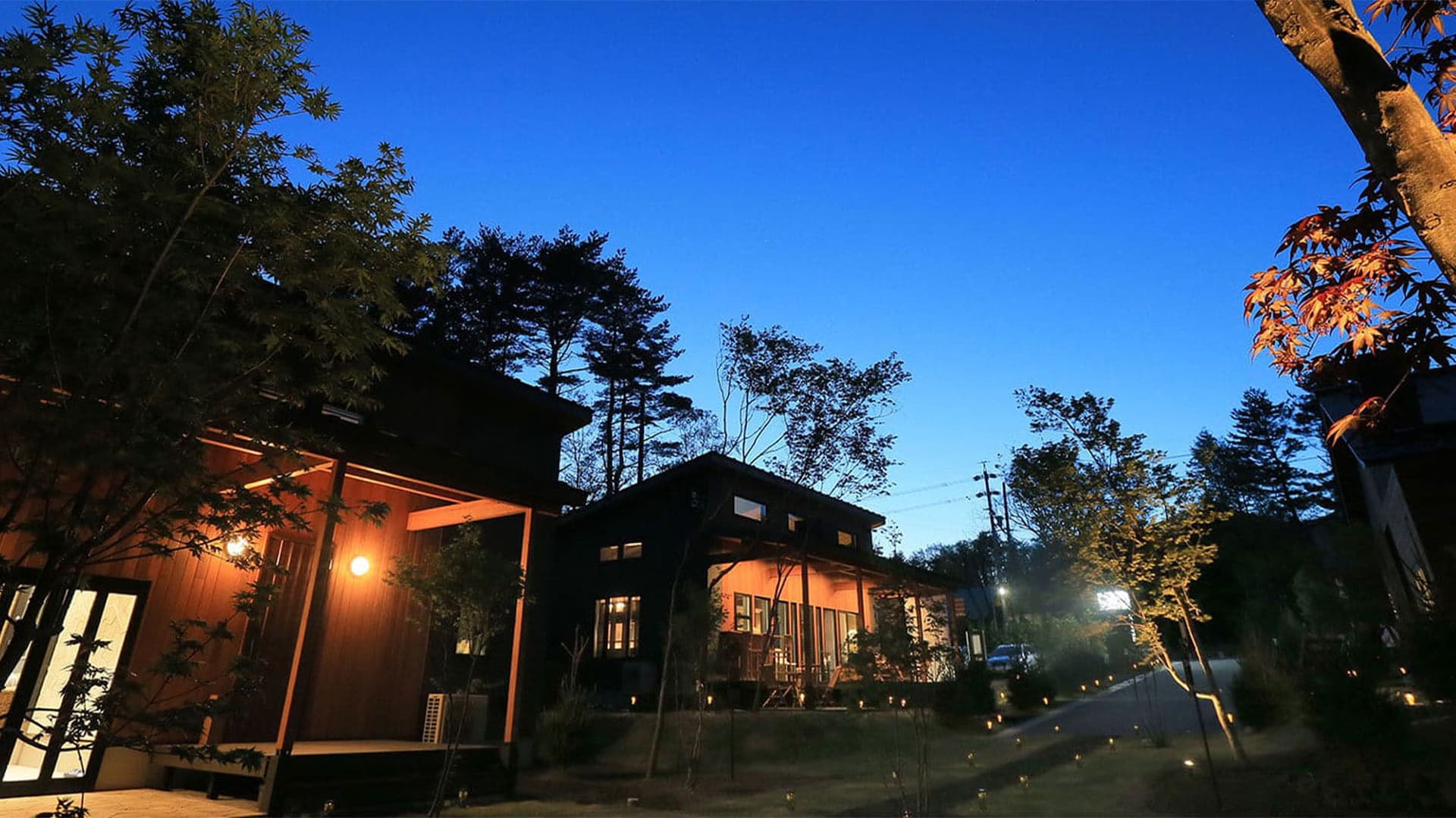 画像:夜の明かりに照らされた木造ゲストルームの外観